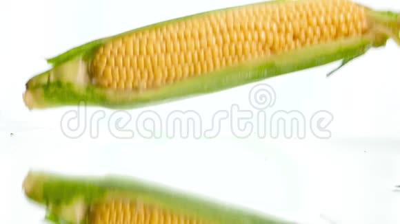特写慢条斯理的玉米芯落在潮湿的白色表面和溅水视频健康观念视频的预览图
