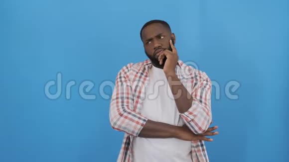 年轻的非裔美国男子穿着t恤站在蓝色背景上手指着成功的手指视频的预览图