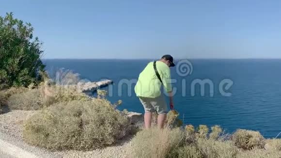 年轻人站在海上的悬崖上拿着石头扔在海上多利在视频的预览图