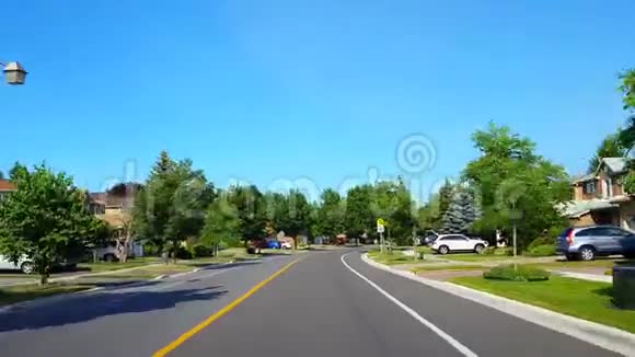 在夏季白天树木茂盛的住宅区道路上反向行驶接近停车标志视频的预览图