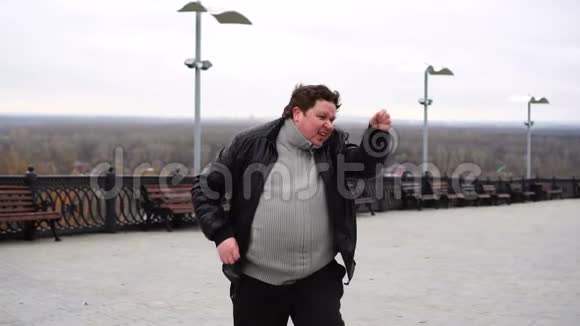 放大了大肚子胖子的肖像在户外跳舞视频的预览图