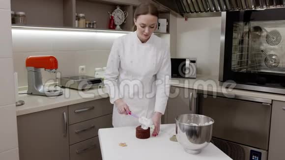在专业厨房里穿着白色长袍的糖果女人用meringue装饰复活节蛋糕视频的预览图
