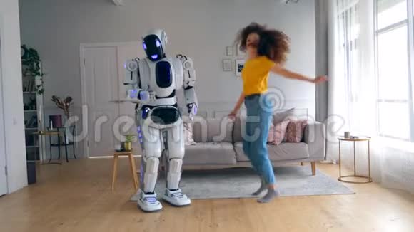 快乐的女孩跳在沙发上而机器人跳舞机器人半机器人和人类概念视频的预览图
