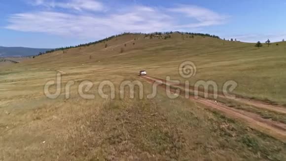 空中镜头拍摄与无人驾驶皮卡在草原汽车沿着草原行驶到西伯利亚铺设道路视频的预览图