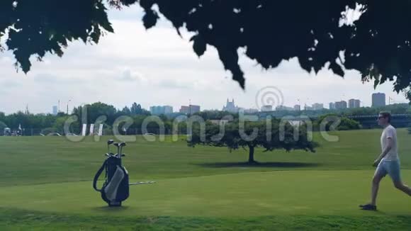 一个人正沿着高尔夫球场散步带着一个高尔夫球杆出去视频的预览图