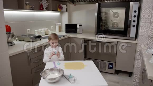 小男孩在漂亮的灯光厨房里玩饼干形状帮助妈妈做饭视频的预览图