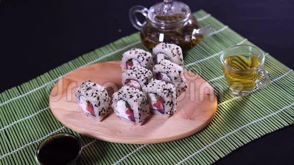 装饰竹餐巾纸上有酱油和绿茶的美味卷在木板上靠近美味的寿司卷视频的预览图