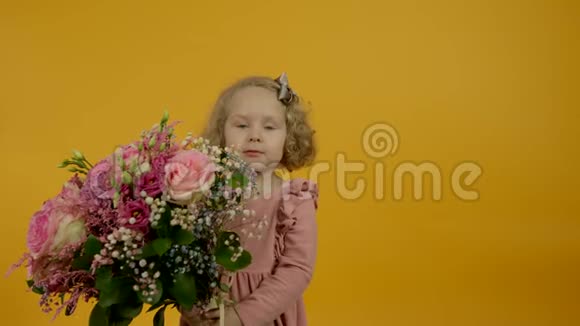 可爱的卷发孩子带着鲜花对着镜头微笑视频的预览图