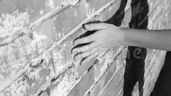 那个十几岁女孩的手沿着一堵砖墙转动她的手指独自走在危险的工业场所女孩的影子视频的预览图