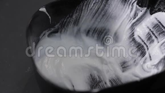 理发师用刷子从黑色的碗里舀出白色的油漆关闭4K视频的预览图