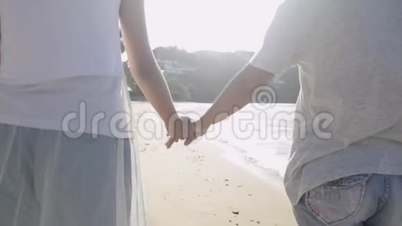 夏天妈妈和女儿一起在阳光下快乐地在海滩上散步和牵手视频的预览图