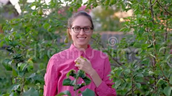 年轻女子农夫从树上摘下一个梨的肖像视频的预览图