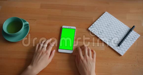 女人的手绿色屏幕智能手机在桌子上缓慢移动视频的预览图