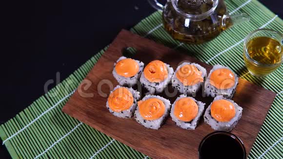 将美味的寿司卷贴在木板上在装饰的竹巾上涂上酱油女人手拿寿司视频的预览图