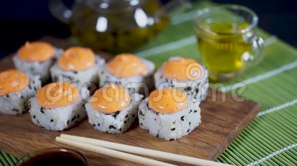 装饰竹餐巾上的木板上有辣酱的美味卷提供美味的寿司卷视频的预览图