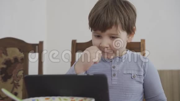 男孩在平板电脑上看卡通而母亲在工作有趣的情绪视频的预览图