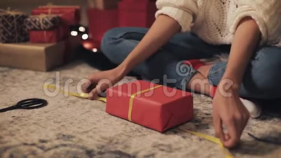 紧紧抓住女孩的手最后包装圣诞礼物女孩在家里地板上绑着黄色丝带视频的预览图