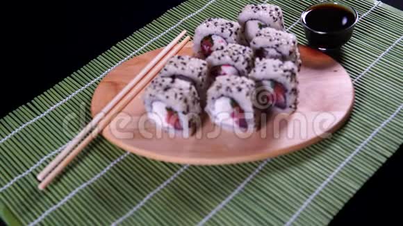 将美味的寿司卷贴在木板上用酱油和筷子夹在装饰的竹巾上视频的预览图