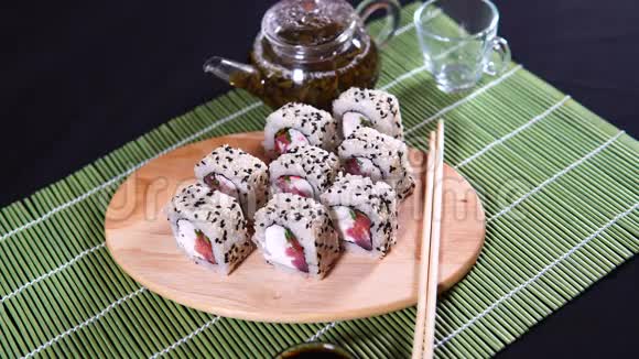 在装饰竹餐巾纸上用筷子和茶壶里的绿茶在木板上做美味的面包靠近美味视频的预览图
