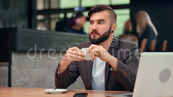 在使用笔记本电脑工作期间一位精力充沛的商务男性在咖啡馆享受咖啡休息视频的预览图