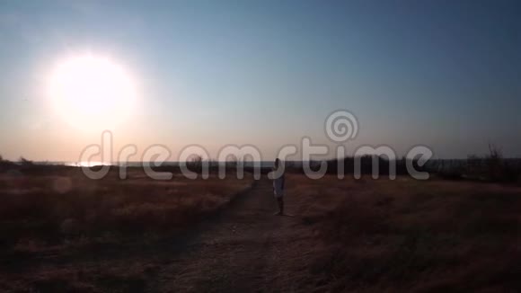 一个女孩独自站在一条土路上在干燥的田野之间视频的预览图