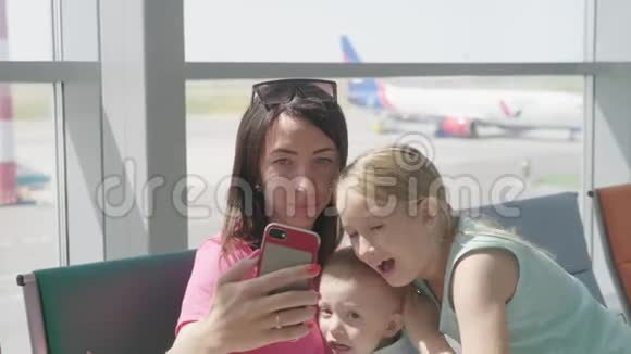 家人在等待飞机时用智能手机自拍家人在国际机场等候航班视频的预览图