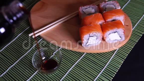 装饰竹餐巾纸上有酱油的木板上的美味卷提供美味的寿司卷视频的预览图