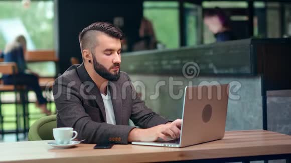 在舒适的咖啡馆里用笔记本电脑进行商务聊天打字的男性自由职业者程序员视频的预览图