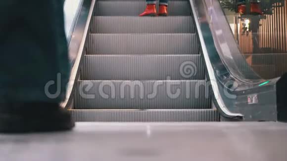 人们在商场的自动扶梯电梯上移动的腿购物中心的顾客站在自动扶梯上视频的预览图