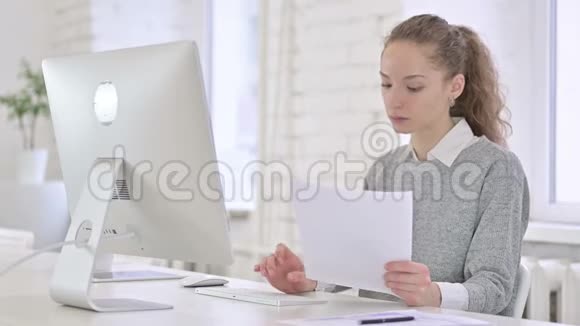 年轻的拉丁妇女阅读文件和工作台式计算机视频的预览图