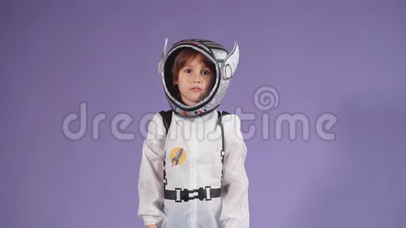 穿着白色防护服和紫色背景头盔的小宇航员男孩视频的预览图