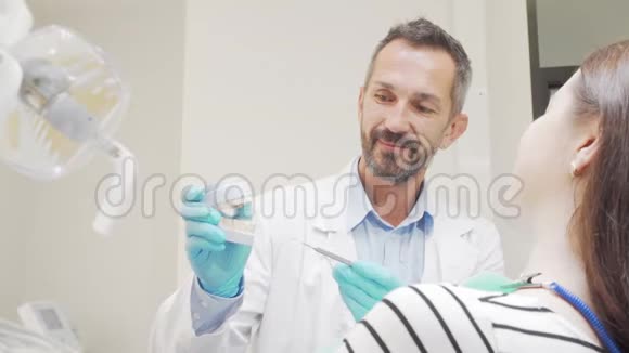 有经验的男牙医在和他的女病人谈话视频的预览图