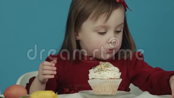女孩为复活节吃蛋糕从他那里吃五颜六色的糖果复活节快乐视频的预览图