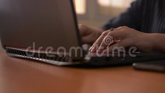 女人的手在电脑键盘上打字用手机女商人在办公室里用笔记本电脑工作视频的预览图