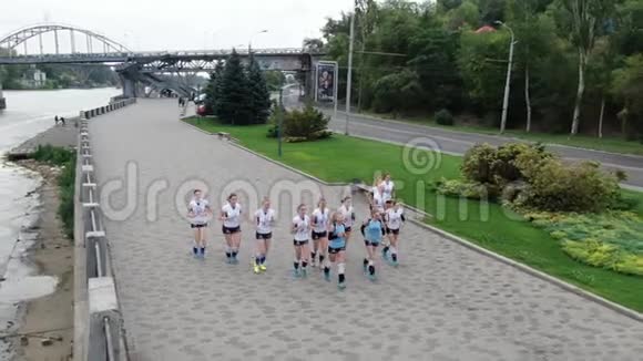 一群年轻女运动员在河边慢跑的空中镜头视频的预览图