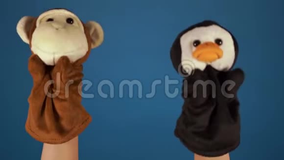 蓝色背景上手上的软木偶玩具木偶戏的概念与木偶猴子和企鹅亲密接触视频的预览图