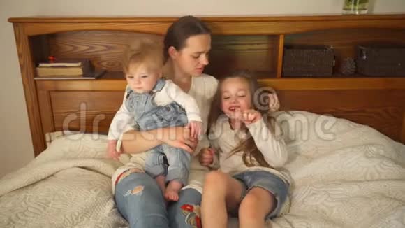 漂亮的母亲和她漂亮的女儿和儿子躺在床上手持射击视频的预览图