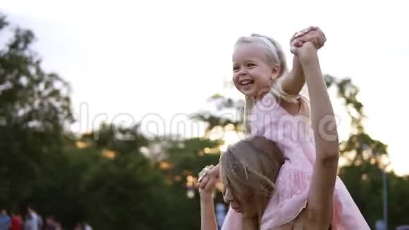 快乐的白种人母亲把美丽的小女儿扛在肩上在公共场合一起跳舞和玩视频的预览图