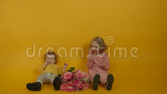 可爱的卷发孩子带着鲜花微笑着吃棒棒糖视频的预览图