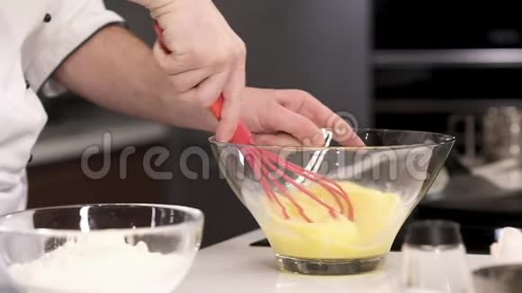 厨师在透明的盘子里积极地鞭打鸡蛋在厨房里煮煎蛋卷视频的预览图