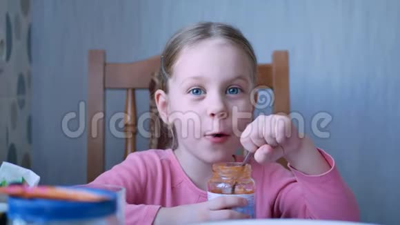 漂亮的小女孩用勺子吃水果酱或酱汁视频的预览图