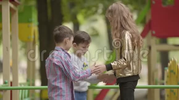 三个可爱的孩子一起在户外玩耍孩子们在操场上无忧无虑的童年视频的预览图