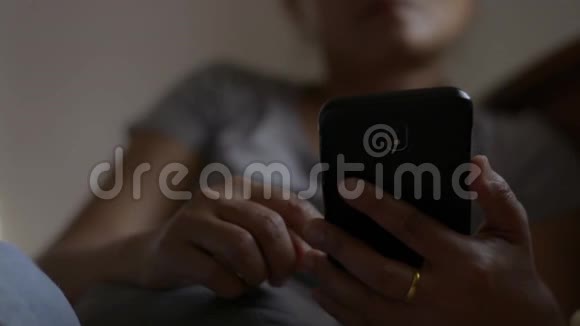 关闭女性手使用手机社交在线亚洲女人在床上用智能手机检查社交应用程序视频的预览图