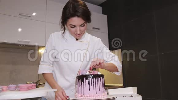 女面包师正在装饰一个生日蛋糕与马克龙在顶部视频的预览图