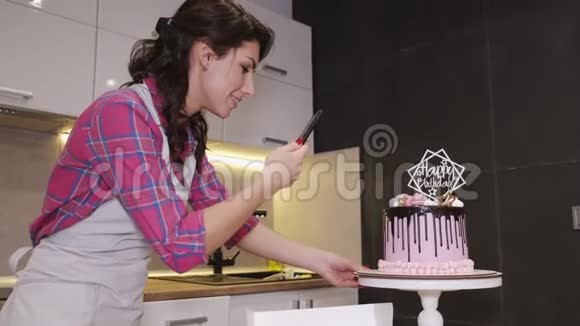 女面包师正在厨房里拍生日蛋糕视频的预览图