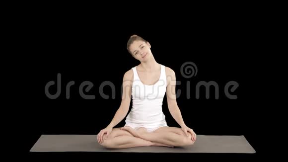 平静的女人练习瑜伽坐在莲花姿势伸展脖子阿尔法频道视频的预览图