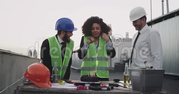 两位建筑师和一位工程师一位非洲裔女士庆祝建筑工地屋顶的生日视频的预览图
