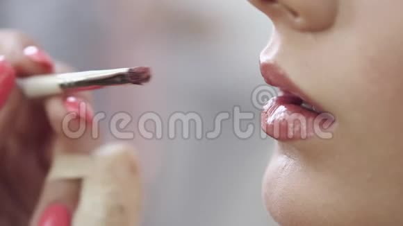 化妆师将化妆品涂在女人嘴唇上视频的预览图
