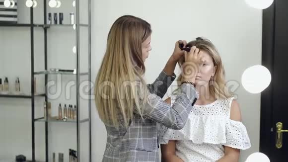 化妆师在沙龙中客户脸上的基础应用视频的预览图