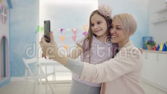 成年女性和小女孩正在智能手机上合影拥抱在镜头前视频的预览图